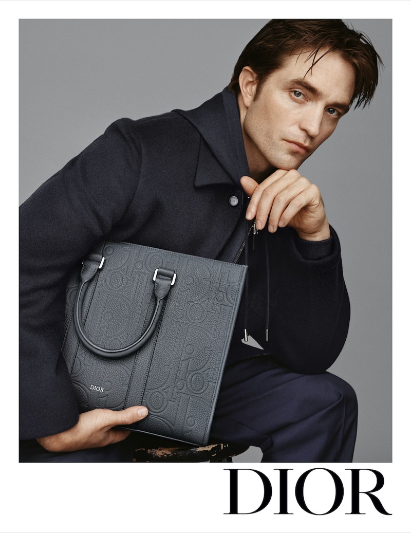 Robert Pattinson poses with a Dior tote adorned with the brand’s Oblique motif. 