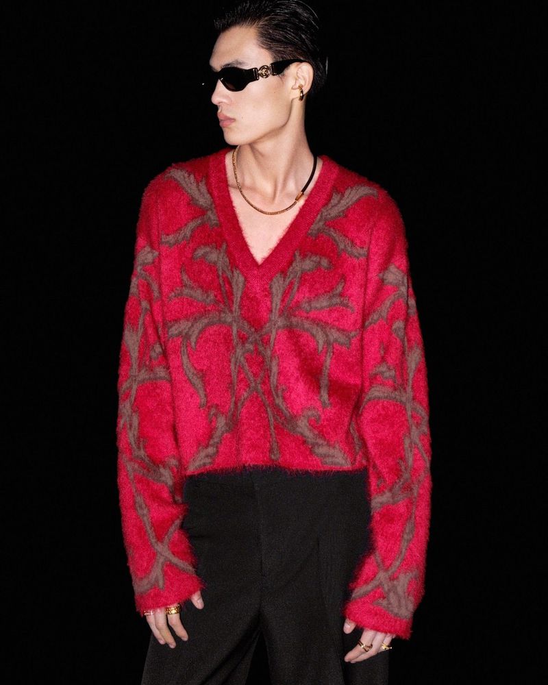 Taking the spotlight, Zhaoyi Fan models a red V-neck sweater by Versace.